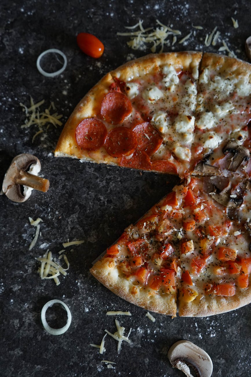 Several different artisan pizzas with colorful toppings arranged on dark counter viewed from above
