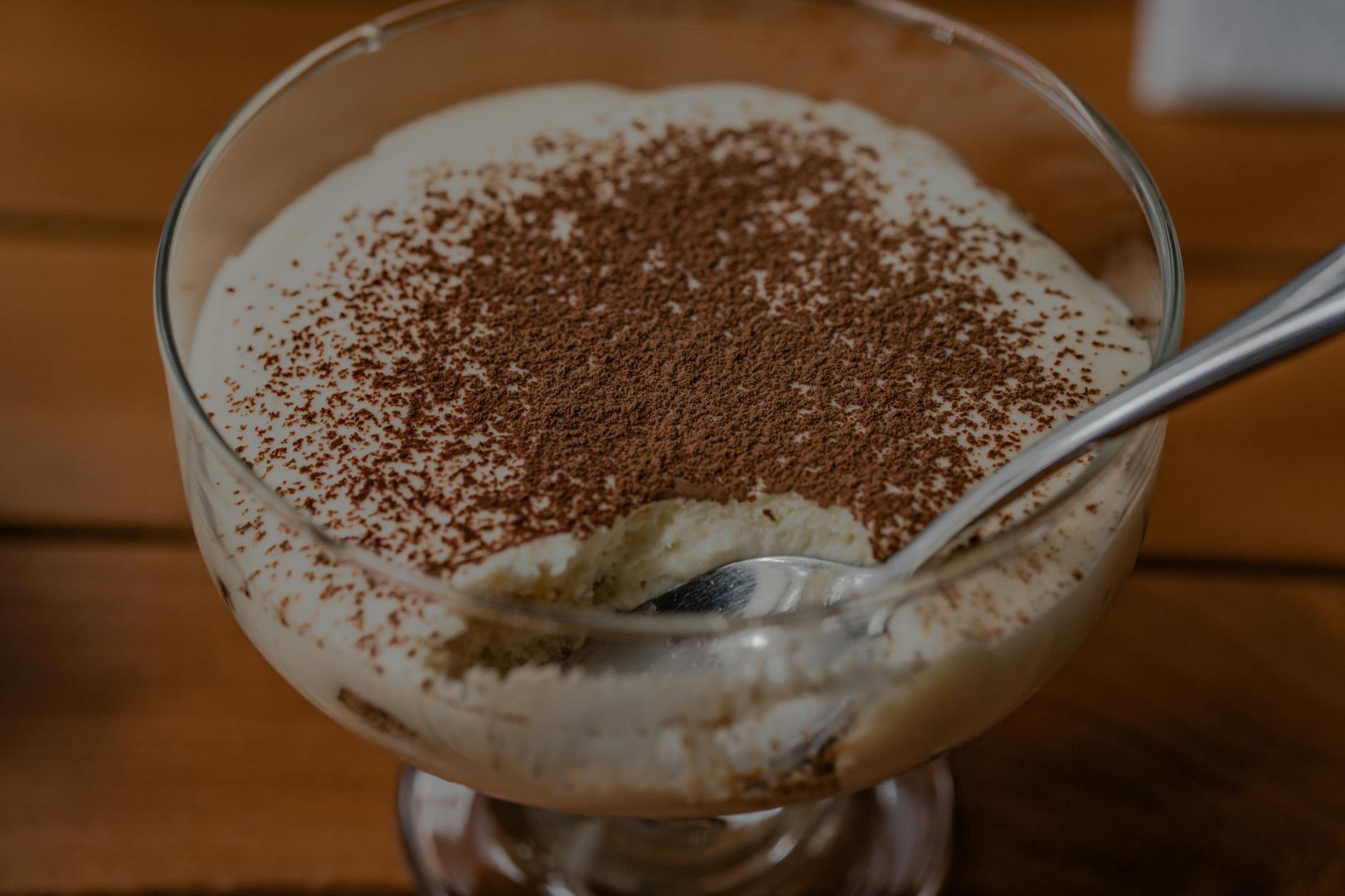 Classic Italian tiramisu dessert served in clear glass cup with cocoa powder dusting